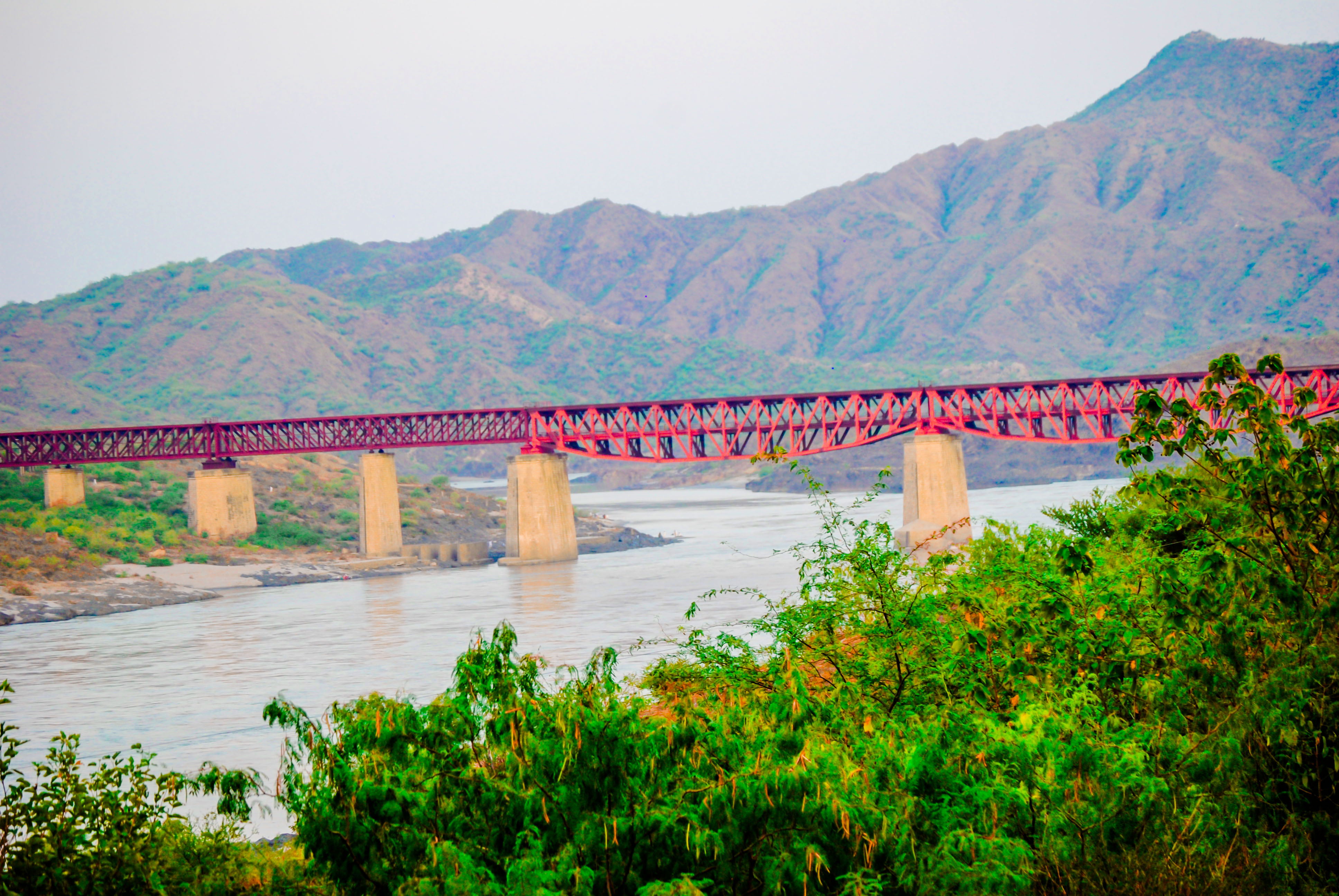 Attock Bridge crossing the Indus River, with green riverbanks and hills